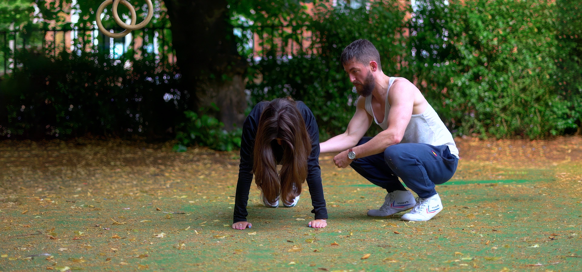 Personal trainer guiding a client's form during a bodyweight gymnastic ring exercise in Glasgow