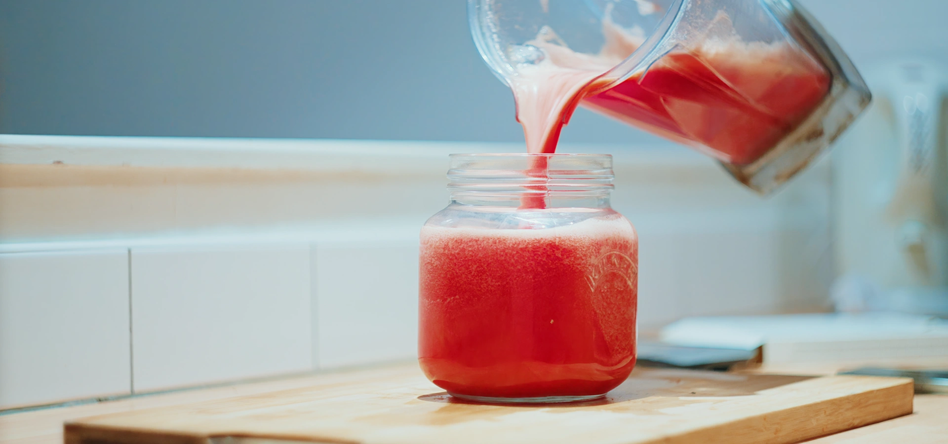Pouring a nutrient-dense juice into a mason jar as part of functional nutrition coaching