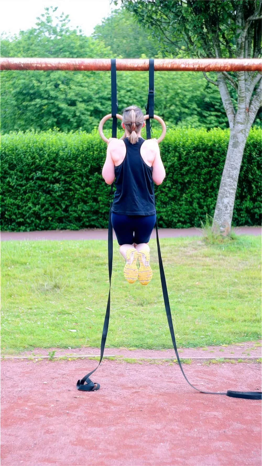 Yolander performing a ring pull-up outdoors as part of her bodyweight strength coaching with Euphonic Health