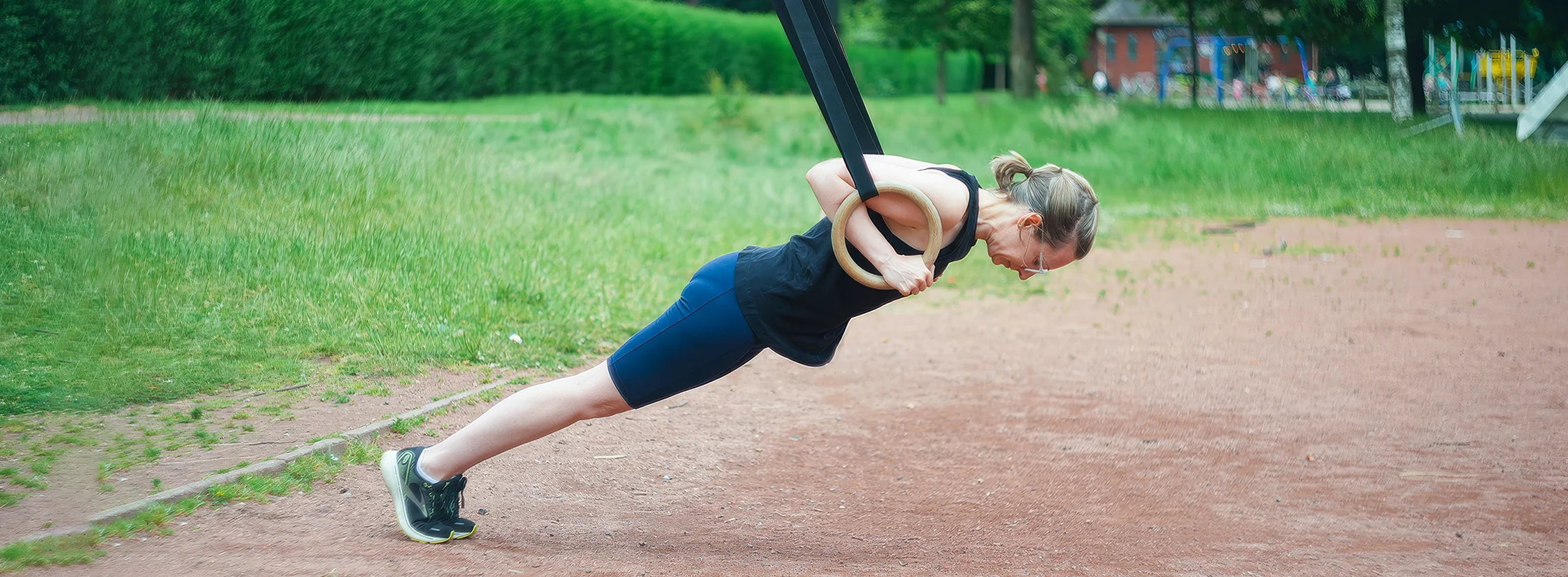 Yolander performing a ring press-up outdoors as part of her bodyweight strength coaching with Euphonic Health